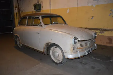 En rostig lloyden bil står i ett garage.