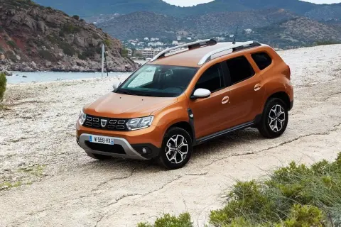 Pomarańczowy Dacia Duster na drodze szutrowej. Wiele osób szuka dacia duster opinie forum, by dowiedzieć się więcej o tym modelu.
