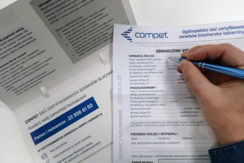 Dłoń z długopisem wypełniająca formularz oświadczenia sprawcy kolizji drogowej.
