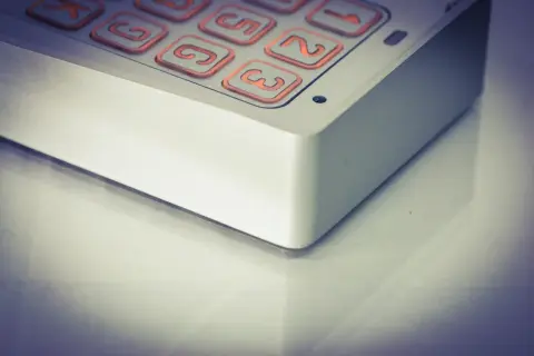 Zbliżenie na klawiaturę domofonu z podświetlanymi na pomarańczowo przyciskami.