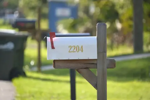 A white mailbox with the number 2204, mounted on a wooden post, ready for mail delivery. This image could be a visual guide on how to install a mailbox.