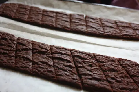 Två rader med sega chokladsnittar på bakplåtspapper, redo att gräddas.