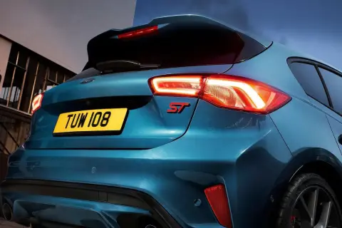 Tylna część sportowego Forda Focus ST 2025 w kolorze niebieskim, z podświetlonymi światłami i czerwonym emblematem ST.