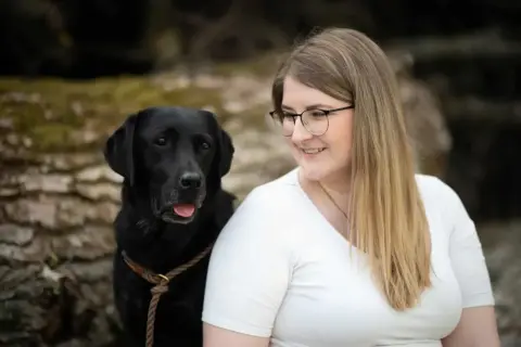Ein schwarzer Labrador und eine Frau mit Brille lächeln. Perfekt für eine vorlage trainingsplan hund.