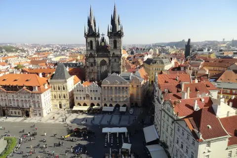 Blick über die Dächer der **Prag Stadt** mit der Teynkirche im Zentrum. Menschen beleben den Platz.