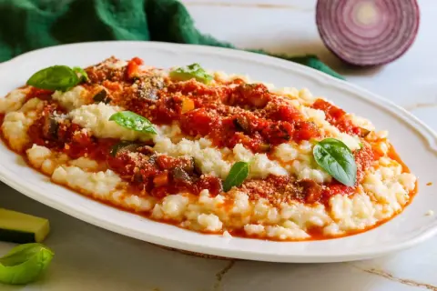 Frascarelli ricetta originale: un piatto cremoso con sugo di pomodoro, verdure e parmigiano, guarnito con basilico fresco.