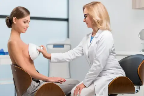 Lekarka wykonuje badanie USG piersi. Warto wykonać je w profesjonalnym gabinecie diagnostycznym.