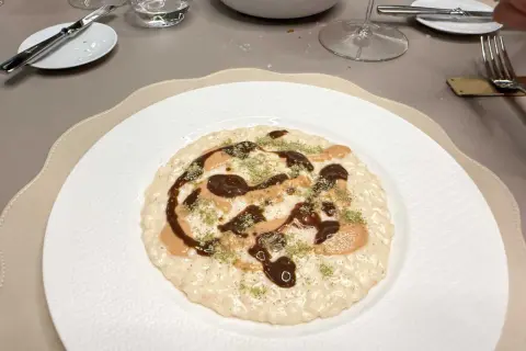 Un risotto cremoso con salse scure e chiare, guarnito con erbe verdi. Andrea la Rossa lo ha preparato con cura.