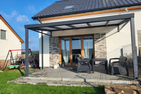 Nowoczesna pergola z poliwęglanowym dachem chroni taras z meblami. Idealne miejsce na relaks.