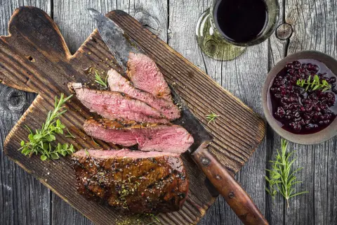 Skivad tagliata med rosmarin och en bärsås, perfekt till ett glas rött vin.