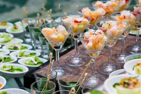 Eleganckie menu na wesele: krewetki z owocami w kieliszkach, sałatki i przystawki w małych miseczkach.
