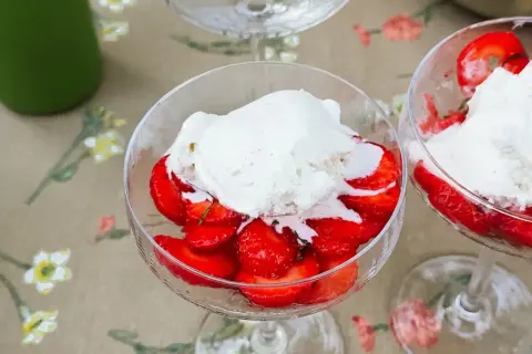Två glas med limemarinerade jordgubbar och vaniljglass på ett blommigt duk.