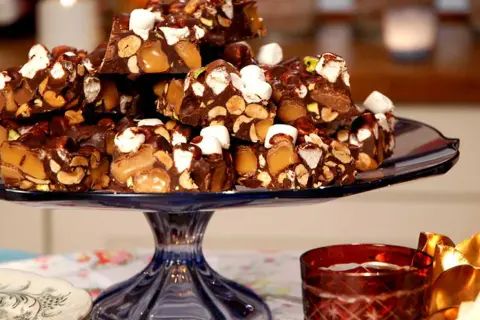 En hög med chokladbitar med nötter, karamell och marshmallows. En härlig rocky road-frestelse på ett blått fat.