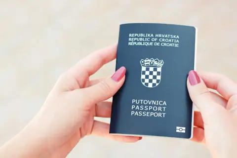 Dwie dłonie trzymają paszport Republiki Chorwacji. Czy do Chorwacji potrzebny jest paszport? Tak, ten dokument jest niezbędny do podróży.