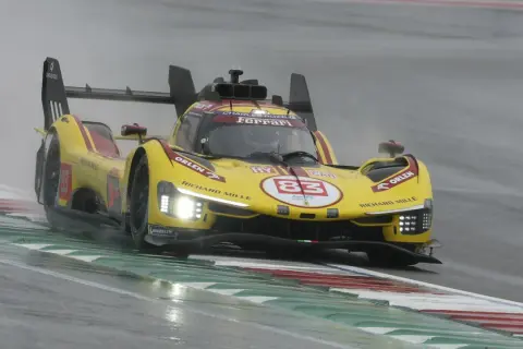Żółty bolid Ferrari z numerem 83 na torze podczas deszczowego wyścigu 24h Le Mans.
