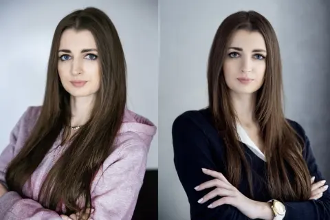 Dwie kobiety, jedna w bluzie z kapturem, druga w eleganckiej marynarce, obie z rękami skrzyżowanymi na piersi.