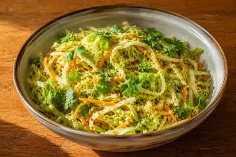 En skål med asiatisk kålsallad med strimlad kål, morötter, koriander och sesamfrön.
