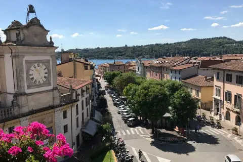 Vista dall'alto di Salò, con il lago sullo sfondo. Un orologio segna l'ora su un edificio storico.