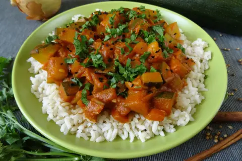 Pyszna cukinia w curry z ryżem, posypana świeżą natką pietruszki i czarnuszką. Aromatyczne danie, które zachwyci każdego.