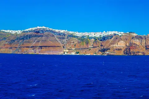 Widok na białe miasteczko na klifie nad błękitnym morzem na Santorini.