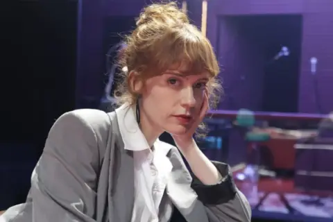 Itsaso Arana, con su cabello recogido y un gesto pensativo, posa con un traje gris sobre una camisa blanca.