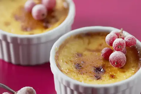 Deux flans aux œufs, dorés et caramélisés, ornés de groseilles givrées. Un délice visuel et gustatif.