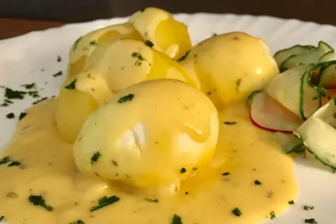 Senfeier rezept: pochiere Eier in cremiger Sauce mit Kartoffeln und einem frischen Gurkensalat.