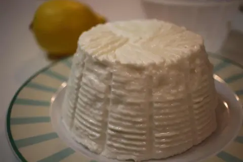 Un fiadone crémeux, prêt pour la recette des Carnets de Julie, avec un citron flou en arrière-plan.