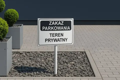 Znak "Zakaz parkowania - teren prywatny" na tle nowoczesnego budynku i zieleni.