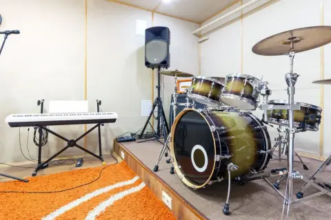 Ein Schlagzeug mit einem großen Bass-Instrument, Keyboard, Mikrofon und Lautsprecher in einem Aufnahmestudio.