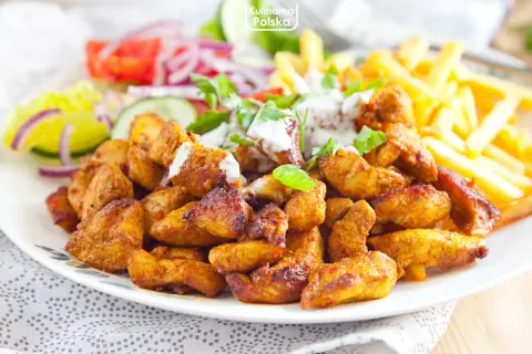 Pyszna shoarma z kurczaka z frytkami i świeżymi warzywami, polana sosem. Idealny posiłek na szybki lunch.