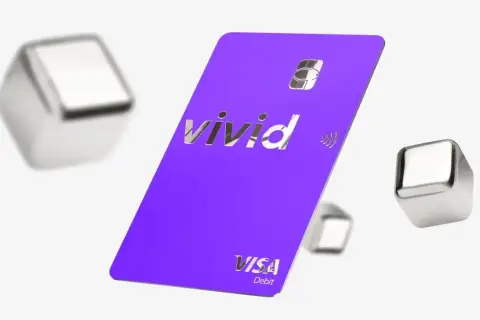 Fioletowa karta płatnicza Vivid Visa Debit, otoczona metalicznymi sześcianami, symbolizuje dostęp do żywych pieniędzy i nowoczesnych płatności.