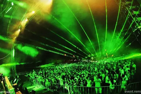 Tłum ludzi na festiwalu **Audiolake** pod zielonymi laserami i światłami.