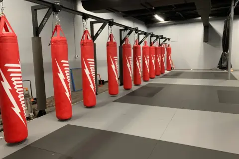 A row of red punching bags hangs from a metal rack, demonstrating how to hang a punching bag for optimal training.