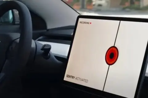 Teslas mittskärm visar "SENTRY ACTIVATED" med en röd ögonliknande ikon. Bilen är redo att agera som en vaktpost.