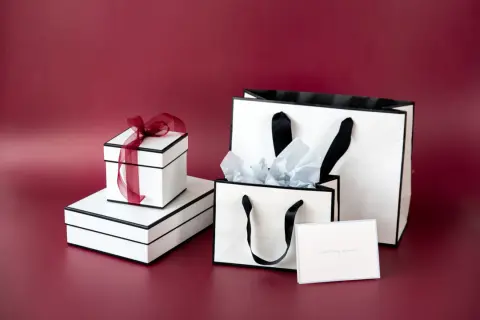Vita presentaskar och påsar med svarta band. En presentinslagning påse med silkespapper och ett kort med texten "something special".