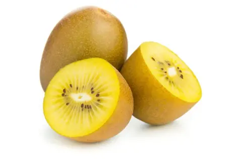 Kiwi amarillo entero y cortado por la mitad, mostrando su pulpa dorada y semillas negras. Descubre sus increíbles kiwi amarillo propiedades.