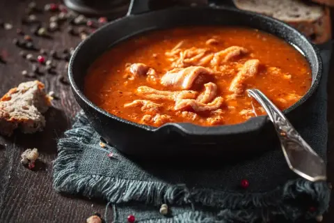 Gorące flaki w głębokim talerzu, z chlebem i pieprzem. Idealne przyprawy do flaków podkreślają smak tej tradycyjnej potrawy.