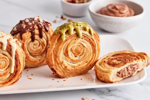 Saftige New York Rolls mit Schokolade, Pistazie und weißer Glasur, eine köstliche Versuchung.