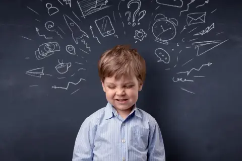 Chłopiec z grymasem na twarzy, nad którym rysunki symbolizujące chaos myśli, może odzwierciedlać zaburzenia pamięci krótkotrwałej u dzieci.