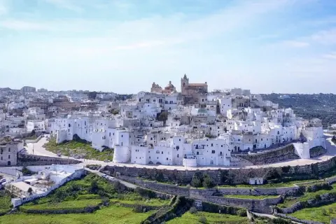 Panoramica di uno dei borghi medievali in Puglia, con case bianche a picco sul mare e un cielo azzurro.