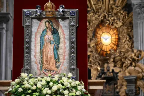 Matka Boża z Guadalupe, jej przesłanie pokoju i nadziei, w otoczeniu kwiatów i ozdobnej ramie, w kościele.