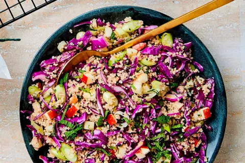 En färgstark couscous sallad med rödkål, äpple och färska örter. En gyllene sked vilar i den fräscha rätten.