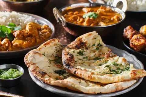 En härlig måltid med indisk mat, inklusive naanbröd, ris och curry. Perfekt för en kväll med vin till indisk mat.