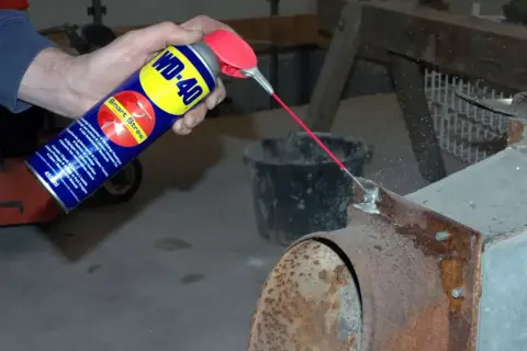 WD-40 wird auf einen verrosteten Kaminofen gesprüht, um Rost zu entfernen.