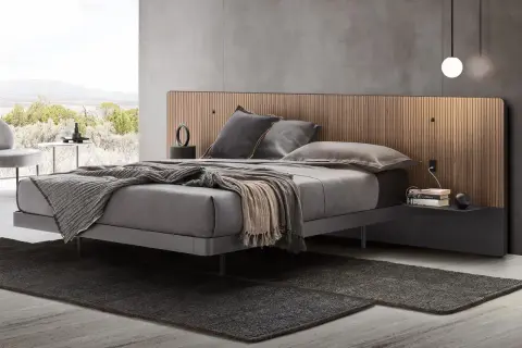 Elegante camera da letto con letto grigio e testiera in legno. Il colore grigio abbinamento crea un'atmosfera rilassante.