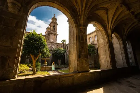 Una mujer contempla el patio interior del monasterio de Poio, con su fuente y campanario al fondo.