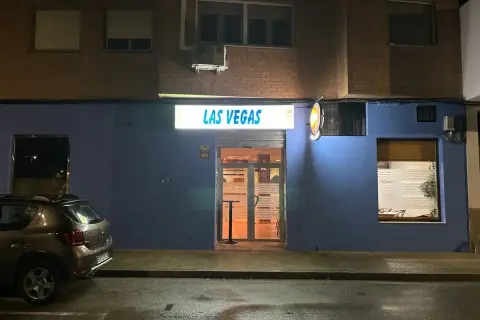 Fachada de "Las Vegas" en Zaragoza, con un coche aparcado y la calle mojada.