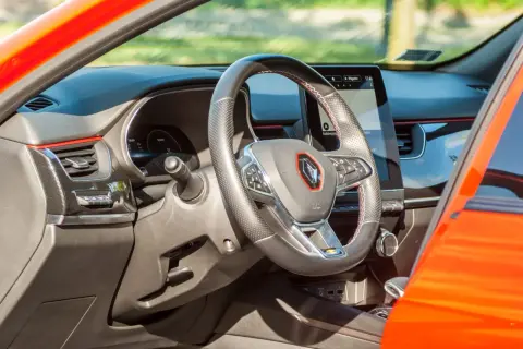 Nowoczesne renault arkana wnętrze z ekranem multimedialnym i kierownicą obszytą skórą. Czerwone akcenty dodają sportowego charakteru.