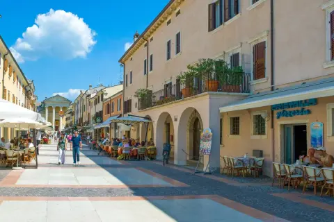 Passeggiata nel bardolino centro storico, con tavolini all'aperto e gente che gode del sole.